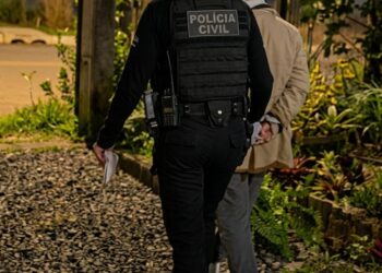 Uma policial levando uma pessoa presa