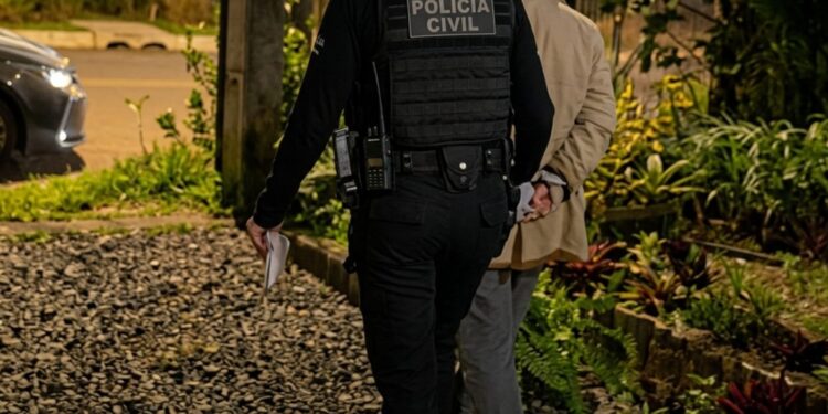 Uma policial levando uma pessoa presa